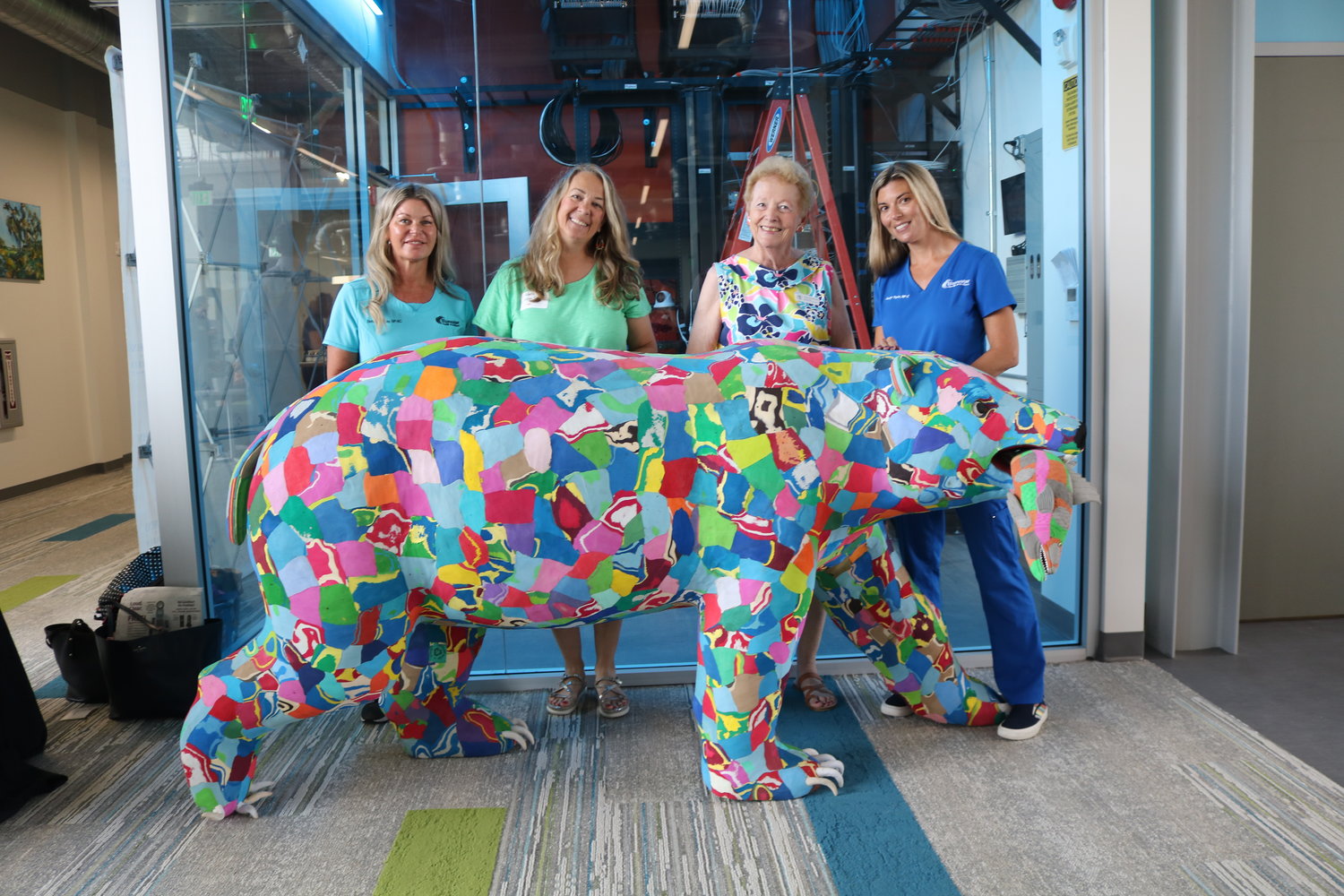 Brittney Schmid, Michelle Smith, Jackie Smith and Jaclyn Taylor stand behind a sculpture of a grizzly made by Ocean Sole entirely of discarded flip-flops. The sculpture is one of several at the link.